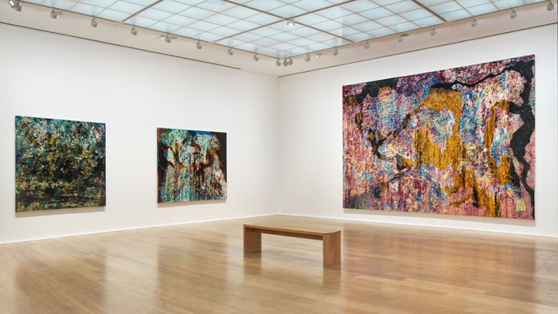 نمایی از آثار سوررئالیستی Man Ray در گالری موزه متروپولیتن نیویورک، با نورپردازی ملایم و بازدیدکنندگان در حال تماشای فوتوگرام‌ها