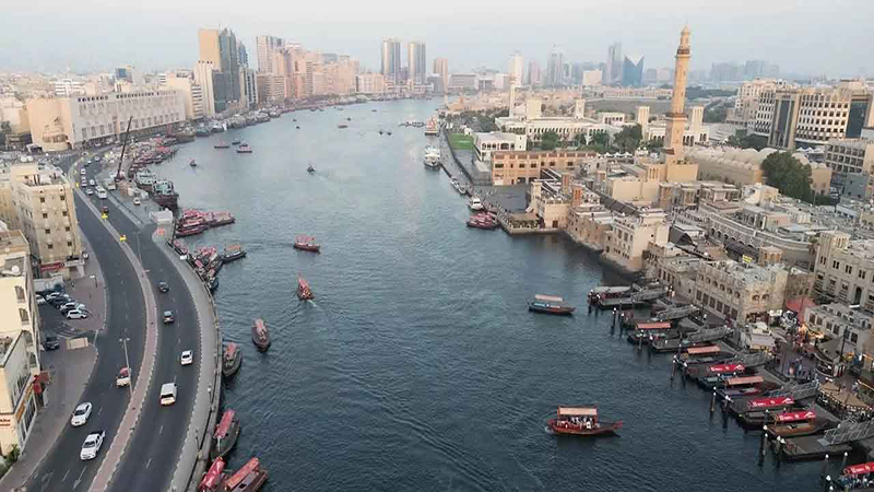 تصویر مکان‌های دیدنی اطراف نهر دبی شامل موزه دبی، بازار طلا، بازار ادویه، Heritage Village و اسکله قایق‌سواری با منظره‌ای از آبراه تاریخی شهر