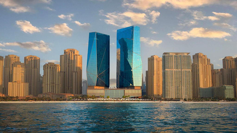 نمای بیرونی Rixos Premium Dubai JBR با طراحی شیشه‌ای مدرن، نورپردازی شبانه و چشم‌انداز ساحل جمیرا